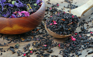 blended tea. black tea with dry flower petals. dry black tea leaves in a wooden spoon. close up