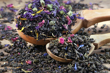 blended tea. black and green tea with dry flower petals and fruits. dry tea leaves in a wooden...