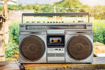 Retro old radio tape cassette on wooden table outdoor.