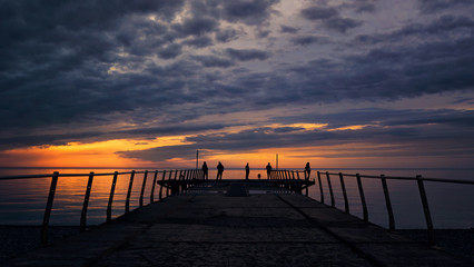 Fototapeta na wymiar Pier fishermen at sunset dark clouds