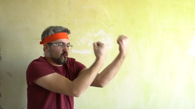 Bearded man against the wall. Good mood. Engaged in martial arts. Repair work in the room. Frick.