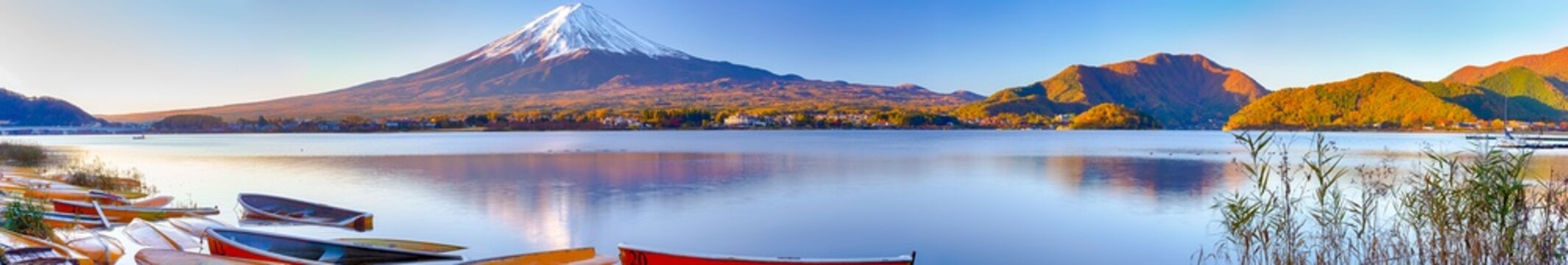 Japan Travel Destinations. Panoramic Image of Renowned Marvelous Fuji Mountain At Kawaguchiko Lake in Japan With Line of Colorful Boats in Foregound.
