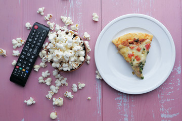 top view of pizza, popcorn and Tv remote on table 