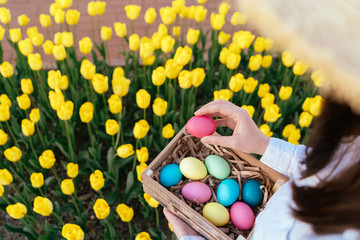 Fototapeta na wymiar woman holding easter colorful eggs with yellow tulips on background.