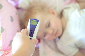Measuring the temperature of small child with contactless thermometer. infrared thermometer in...
