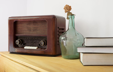 Vintage radio made of wood, green vase and old books on a table