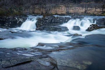 the waterfalls in Glen Orchy near Bridge of Orchy in the Argyll region of the highlands of Scotland during winter whilst the river is flowing fast from rainfall
