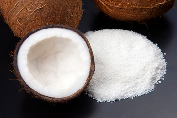 Fototapeta na wymiar Coconut flakes on a dark background next to a coconut. vitamin fruits. healthy food