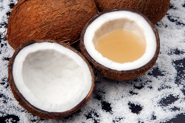 cut fresh coconut with real coconut milk on a background of coconut flakes. vitamin fruits. healthy food