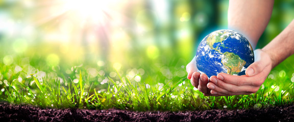 Hands Holding Planet Earth In Lush Green Environment With Soil And Sunlight - Earth Day Concept - Some Elements Of This Image Were Provided By NASA