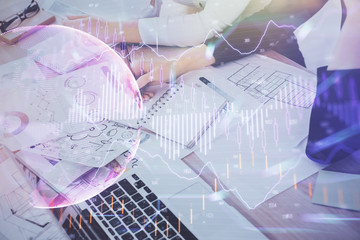 A woman hands writing information about stock market in notepad. Forex chart holograms in front. Concept of research. Double exposure