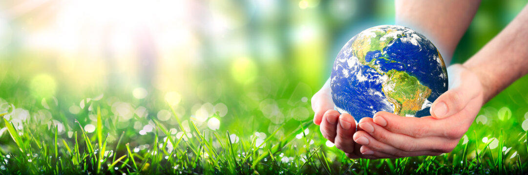 Hands Holding Planet Earth In Lush Green Environment With Sunlight - Earth Day Concept - Some Elements Of This Image Were Provided By NASA