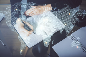 International business hologram over woman's hands taking notes background. Concept of success....