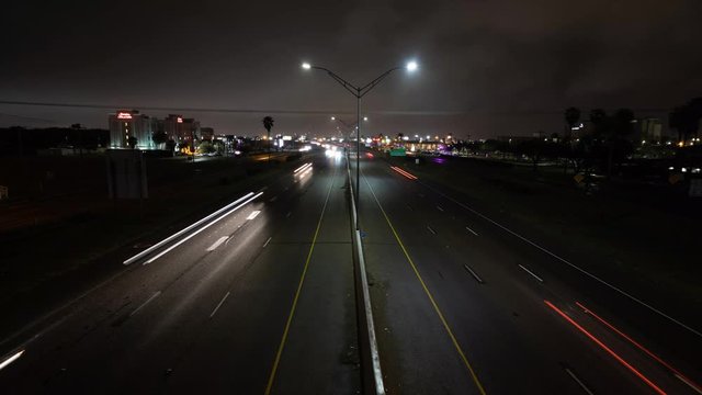 A nighttime time lapse taken from a bridge over the expressway shows the streaks of light moving across the frame, with clouds moving quickly in the sky.