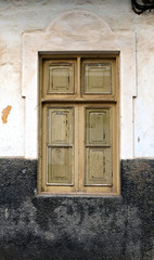 One simple old wooden frame window in an old villa, with closed wooden shutters.