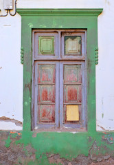 One simple wooden frame gray painted old window in a green wall.