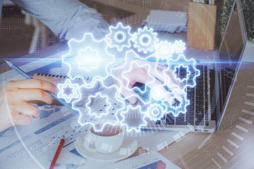 Double exposure of businessman working on laptop on background. International business hologram in...