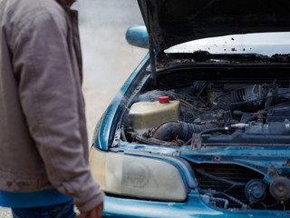 The man got a problem with the car. Boiling water in the engine of an old car.