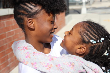 African American Sisters  hugging showing affection looking at each other - Powered by Adobe