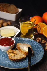 Breakfast, bread and butter with jam and tea on a dark wooden background