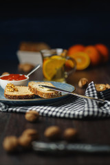 Breakfast, bread and butter with jam and tea on a dark wooden background