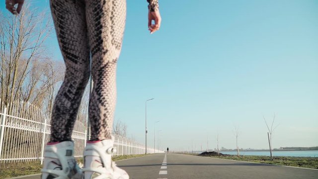 Athletic Slim Rides Girl Roller Skating along the path on the background of a beautiful lake. Slow motion. Shooting on the Steadicam