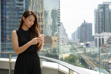 Fototapeta na wymiar Young beautiful Asian businesswoman using phone against view of the city