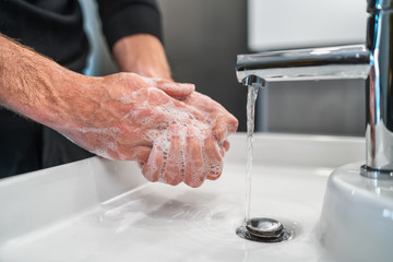 Corona virus travel prevention man showing hand hygiene washing hands with soap in hot water for...