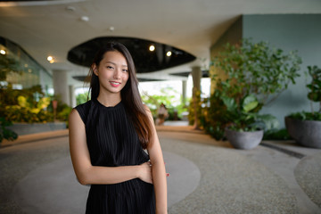 Happy young beautiful Asian businesswoman at the indoor garden