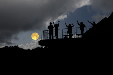 Naklejka na ściany i meble People on terrace with full moon in the evening
