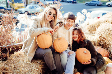 Girls holds pumpkins in hands on the background of the street.