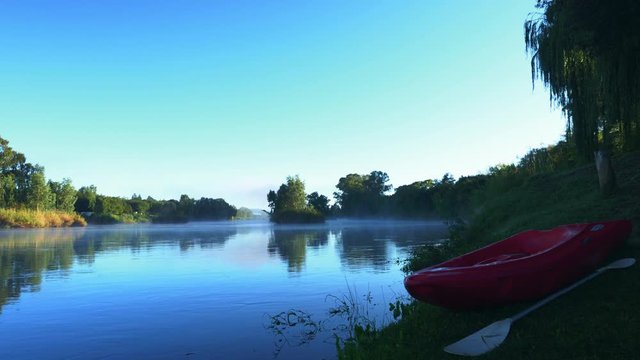 Early morning time lapse of moving river and fog with Kayak in the foreground. (4K)