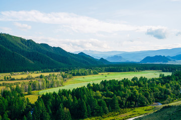 Immense distances with field and forest near countryside. Wonderful mountain land. Great mountains in evening light. Amazing country scenery. Scenic view to vast expanses of rolling hills in sunlight.