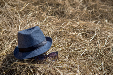 blue hat and sunglasses on dry straw