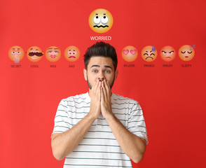 Portrait of worried young man with drawn emoticons on color background