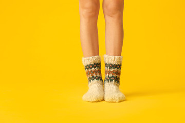 Legs of young woman in warm knitted socks on color background