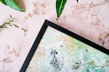 Corner of picture in black frame and decorative dried flowers on pink background. Picture framing concept.
