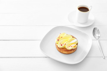 Plate with tasty cake and cup of coffee on table