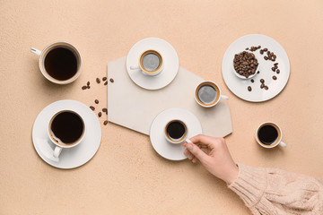 Female hand and cups of different coffee on color background
