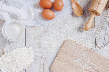 Homemade Dough Recipe (Eggs, flour, milk, sugar) and wooden kneading dough on a wooden table, view...