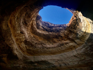 Blue sky through limestone hole in the caves of the Algarve