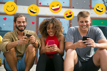 Obraz premium Cheerful focused multiethnic students using their phones and laughing. Mix raced young people holding smartphones with social media chat icons, using online app, texting message. Phone using, concept