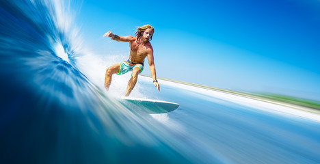 Young man surfer with long hair surfs the fast and perfect ocean wave in Maldives