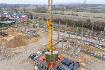 huge concrete pillars are erected on a large construction site using a crane