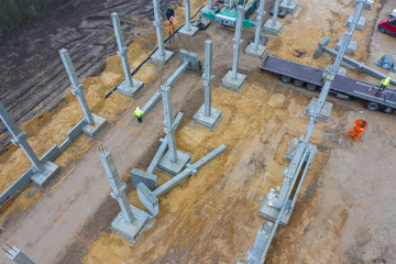 huge concrete pillars are erected on a large construction site using a crane