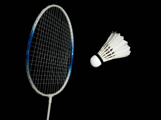 Badminton racket impacting badminton ball or shuttlecock in the black scene. It looks like a ball drops or drop shot. Badminton playing concepts, playing techniques. There is space for a copy space.
