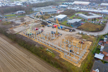 huge concrete pillars are erected on a large construction site using a crane