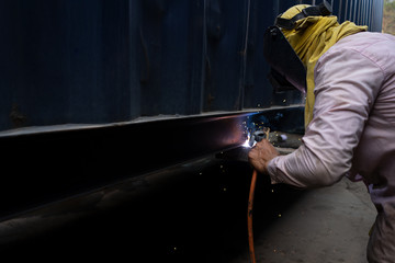 A repairman with welding steel to repairing a container in the container depot service.