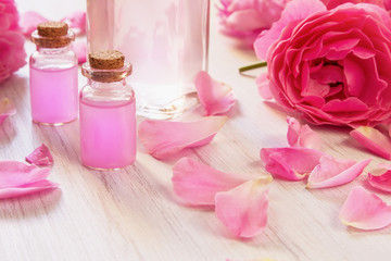 Obraz na płótnie Canvas Glass bottles with rose water and oil, rose flower petals on wooden rustic background, close up