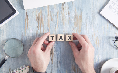 Man showing Tax word on wooden cubes.